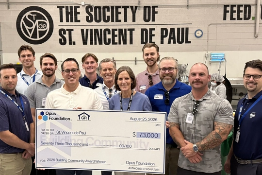 group of smiling people holding a giant check